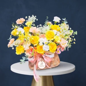 Giỏ hoa sinh nhật đẹp "Nắng Nhẹ An Lành" với tông vàng pastel nhẹ nhàng, kết từ hồng vàng, cát tường, đồng tiền và mimosa, mang ý nghĩa chúc mừng tinh tế và an lành.