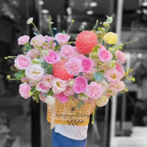 Người đang ôm lẵng hoa tươi sinh nhật với tông màu hồng ngọt ngào, kết hợp nhiều loại hoa.