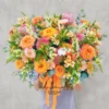 Một người đang ôm giỏ hoa cắm sẵn màu cam – trắng rực rỡ, đại diện cho sản phẩm hoa cắm sẵn gần đây tại Hoa Gửi Yêu Thương.