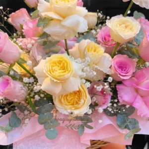 Cô gái trẻ người châu Á ôm giỏ hoa hồng tươi thắm, rạng rỡ tại shop hoa tươi gần trung tâm thương mại.