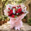 Nhân viên tiệm hoa gần đây đang thiết kế bó hoa theo yêu cầu với hoa hồng đỏ nổi bật trên nền hồng pastel, không gian tươi sáng và chuyên nghiệp.