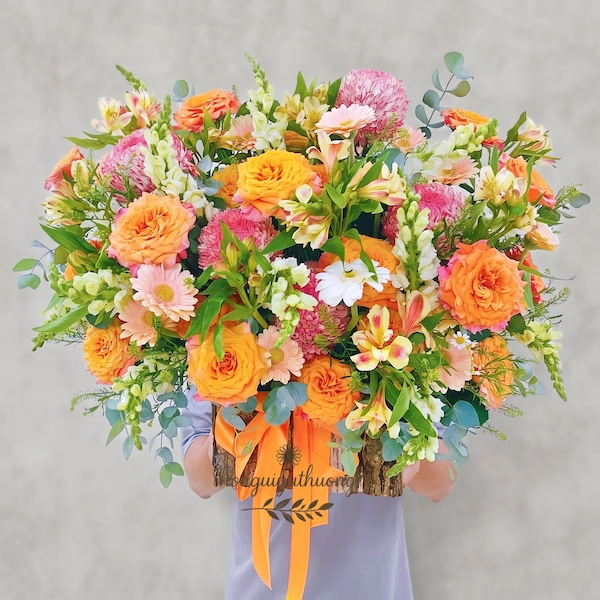 Mẫu giỏ hoa tặng sinh nhật năng động với tông màu cam rực rỡ và sắc hồng tươi tắn từ Pi Flowers & Events, mang lại nguồn năng lượng tích cực cho người nhận.