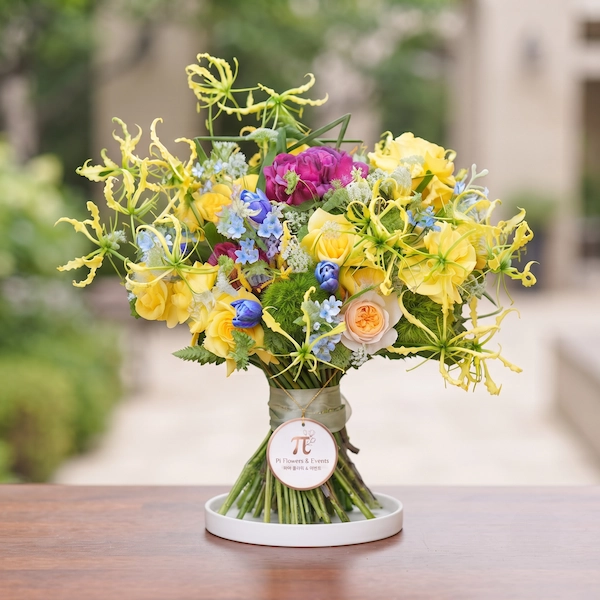 Bó hoa cưới cầm tay kết hợp hoa hồng vàng và hoa lạ rực rỡ tại Pi Flowers & Events.