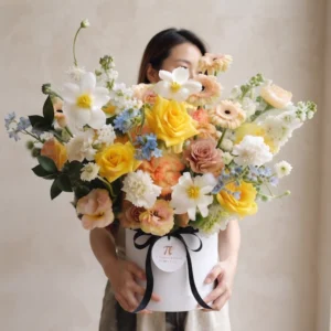 Khách hàng rạng rỡ ôm giỏ hoa sinh nhật tươi dáng cao tone màu vàng kem hiện đại.