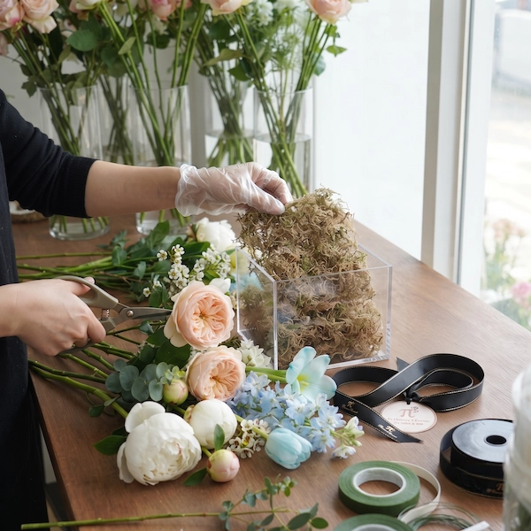 Nghệ nhân đang cắm hộp hoa sinh nhật thiết kế riêng với hoa hồng và tulip.